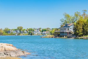 Houses along an ocean cove on a cloudless blue sky