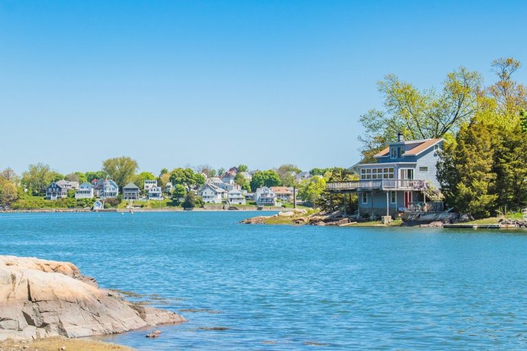 Houses along an ocean cove on a cloudless blue sky