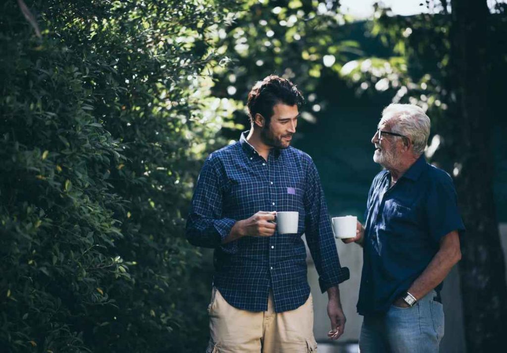 Happy Father and son with coffee cup, standing in garden